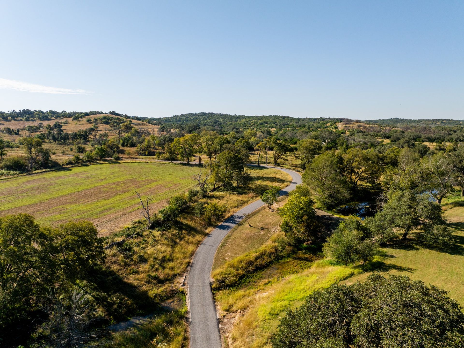 Aerial view of a winding private road crossing a wooded property